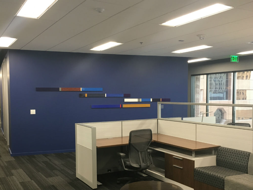 A cubicle with blue walls and a black chair.